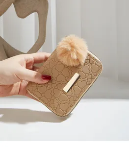 Detailed view of a chic beige women short wallet featuring debossed clover pattern and plush pom.