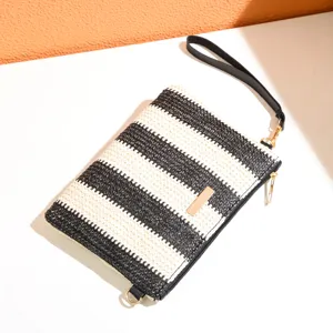 Stylish black and white woven clutch bag featuring a wrist strap and gold tone metal accent.