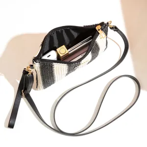 Detailed view of the black and white woven crossbody bag interior capacity with daily items.