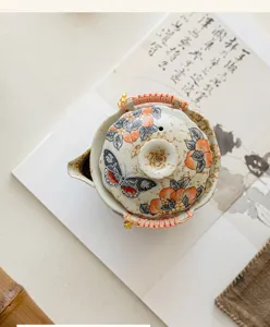 Théière en céramique artisanale ornée de motifs de pêche et de papillon pour le thé.