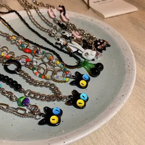 Detailed shot of cute black cat and cherry pendant necklaces, sweet and cool punk style.