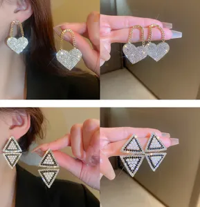 Close-up detail shot of exquisite rhinestone heart and pearl geometric fashion earrings.