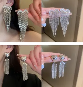 Detailed view of fashionable heart-shaped rhinestone tassel earrings, elegant silver drop design.