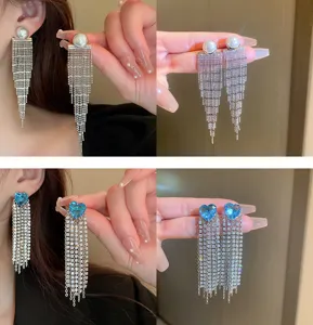 Detail view of sparkly rhinestone fringe earrings with pearl and blue heart accents.