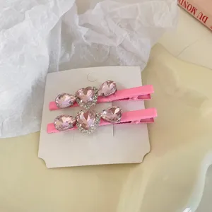 Close-up detail roze strass hart eendebek haarklemmen op witte kaart, elegant ontwerp.