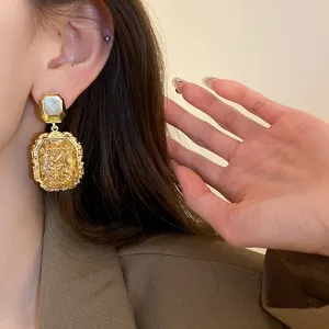 Nahaufnahme der goldenen Vintage Ohrringe im Barockstil am Ohr getragen, edles Schmuckdetail.