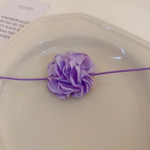 Gros-plan détaillé d'un superbe collier choker fleur en tissu violet au design élégant.