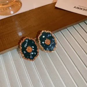 Detaillierte Nahaufnahme von Vintage-Ohrringen im Hofstil mit goldenen floralen Rändern.