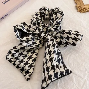 Detailaufnahme des schwarz-weißen Hahnentritt-Haargummis mit Schleife, elegantes Stoff-Haaraccess.