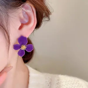 Close-up of elegant purple velvet flower ear studs with golden stamen, chic French retro jewelry.
