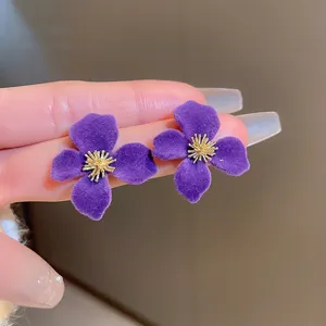 Close-up detail of purple velvet flower stud earrings with gold stamen, elegant vintage style.