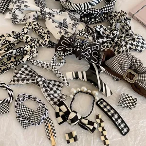 Set mit schwarz-weißen Karomustern, Haargummis, Schleifen und Haarklammern für Damen.