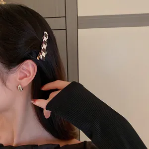 Nahaufnahme einer eleganten schwarz-weißen Karomuster Haarspange für stilvolles Styling.