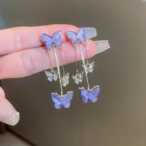 Detailed view of elegant purple rhinestone butterfly dangle earrings with delicate chain links.