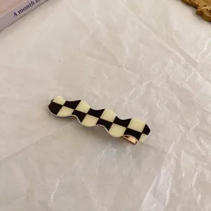 Schwarz-weiße Karomuster Haarklammer Detailaufnahme, stilvolles welliges Design Accessoire.