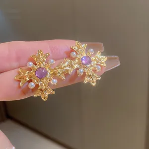 Vintage gold cross earrings featuring purple center stone and dainty pearls, detailed shot.