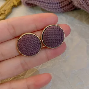 Close-up detail of vintage purple fabric round button earrings with gold twisted trim.
