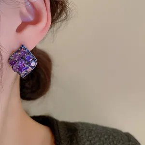 Close-up detail of vintage purple rhinestone stud earrings with sparkling crystals.