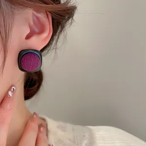 Close-up detail of vintage purple fabric square stud earrings worn on ear, elegant design.