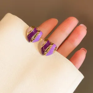Detailed close-up of stylish heart-shaped earrings with purple and gold enamel accents for daily wear.