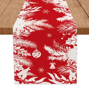 Christmas red table runner fabric detail showing white snowflake and pine branch design.