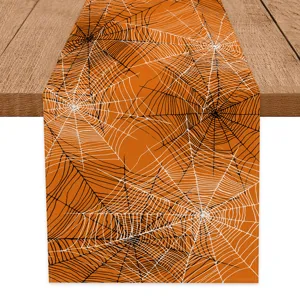 Halloween spider web pattern table runner detail shot, orange decorative fabric mat for dining table.