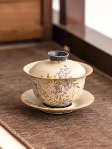 Vue détaillée du bol à thé gaiwan en céramique avec glycine peinte et bordure dorée.