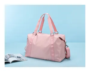 Pink travel duffel bag detail shot, showing durable fabric, double handles and side strap.