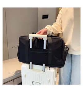 Detail view of black travel duffel bag with trolley sleeve and shoulder strap for luggage.