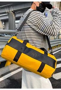 Detailed view of large capacity yellow travel duffel bag, stylish sportswear shoulder bag.