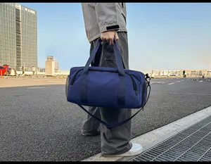 Outdoor detail view of a large capacity blue travel duffel bag with sturdy handles.