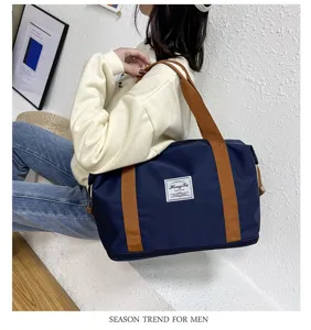 Vista dettagliata della grande borsa da viaggio in tessuto Oxford blu navy con manici marroni.