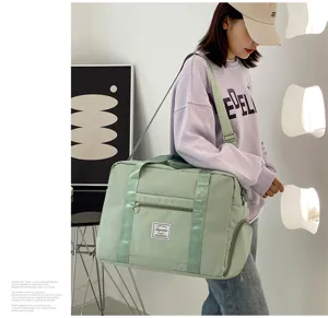 Close-up detail view of a large capacity green travel duffel bag with shoulder strap worn by model.