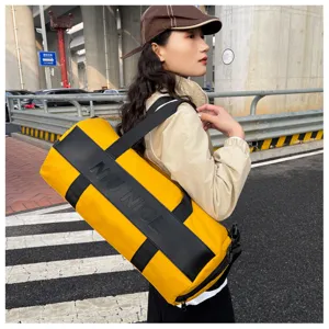 Detailed view of the yellow and black gym duffel bag showing strap and outdoor scene.