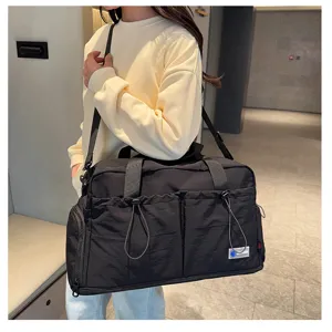 Detail view of the black travel duffel bag worn on shoulder, showing large capacity style.