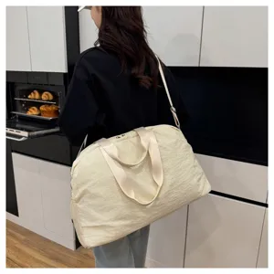 Close-up detail view of large capacity beige travel duffle bag in modern kitchen setting.