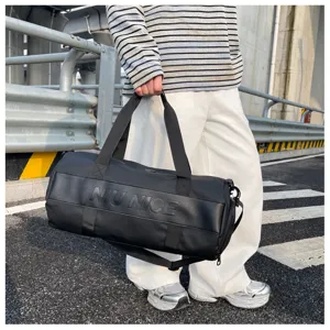 Detail view of black cylindrical fitness travel bag with sturdy handles and shoulder strap.