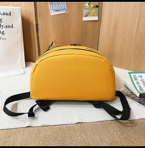Close-up detail of yellow waterproof casual sports backpack with black straps and zippers.