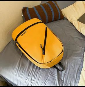 Close-up detail of yellow waterproof leisure backpack showing smooth fabric and slant zipper.