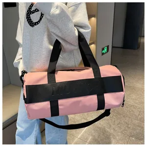 Pink cylinder gym duffel bag with black straps and bold letter print for sports and travel.