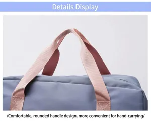 Close-up detail of the pink handle on a gray travel duffel bag, showing sturdy webbing.