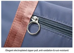 Detailed view of large capacity travel bag zipper and durable metallic puller, grey fabric.