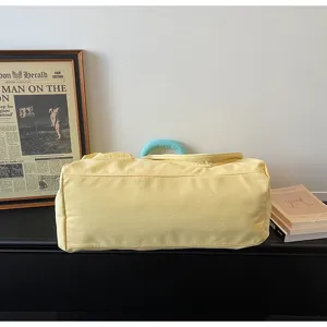 Dettaglio borsa da viaggio sportiva gialla, con manico blu a contrasto e tessuto resistente.