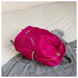 Details of the magenta oxford cloth sports backpack with secure zipper and front pocket design.
