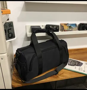 Large capacity black sports travel duffel bag with shoulder strap and shoe compartment detail view.
