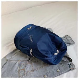Detail view of the navy blue oxford cloth backpack, highlighting durable fabric and dual zippers.