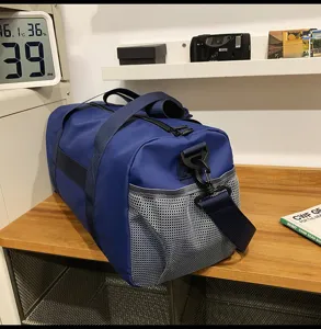 Detail view of the blue travel duffel bag showing side mesh pocket and sturdy strap design.
