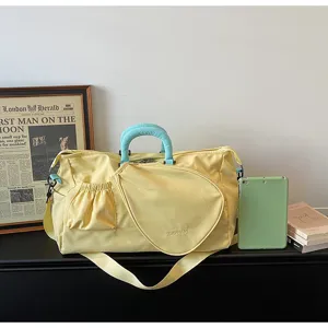 Grande borsa da viaggio sportiva gialla con tasca racchetta e tracolla sul tavolo.