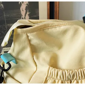 Borsa da viaggio sportiva giallo chiaro in dettaglio, chiusura con zip e pratica tasca anteriore.