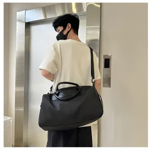 Large capacity black nylon travel duffel bag with leather handles for short outdoor trips.